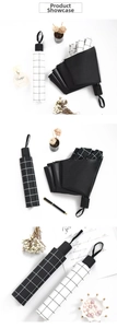 Close-up of black and white checkered folding umbrella with matte handle and wrist strap