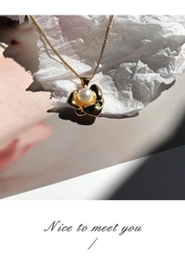 Detailed view of a gold floral petal pendant with a white pearl on a delicate chain