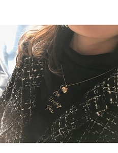 Detail of a golden petal pendant with pearl worn on a model with tweed jacket