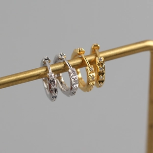 Detail of silver and gold gear hoop earrings with star patterns and inlaid zircons