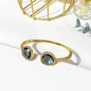Detail of gold open bracelet featuring dark grey pear-cut crystal and zircon accents