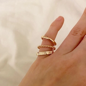 Close-up of three gold-plated 925 sterling silver rings styled on a hand in warm lighting