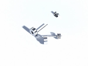 Macro shot of silver gear-shaped stainless steel stud earrings with detailed metallic teeth