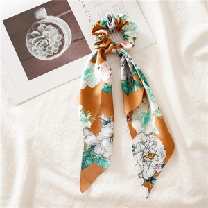 Floral print hair scrunchie with long ribbons in mustard yellow on linen background