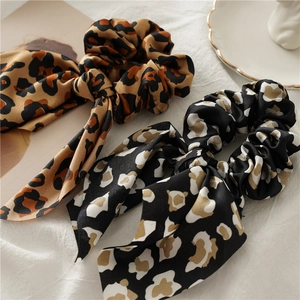 Detail of leopard print satin hair scrunchies with long ribbons on white linen