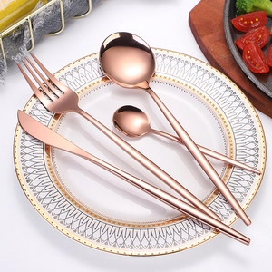 Polished rose gold stainless steel cutlery set with knife, fork, and spoons on a plate