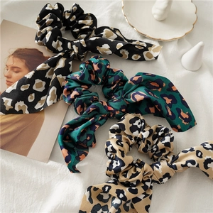 Detailed view of satin leopard print hair scrunchies with long ribbon ties on fabric