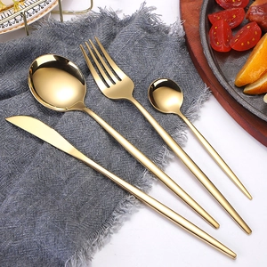 Polished golden stainless steel cutlery set of four pieces on a dark grey linen napkin