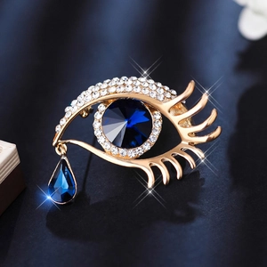 Golden eye-shaped brooch with blue crystals and a teardrop pendant for women