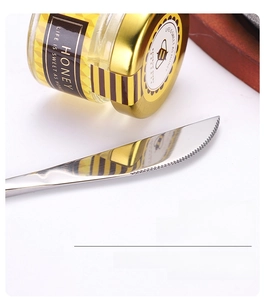 Detail of mirror-polished stainless steel steak knife with finely serrated blade edges