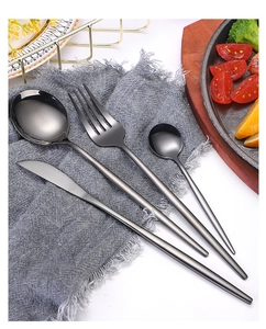 Close-up of black matte stainless steel cutlery set on a grey linen napkin