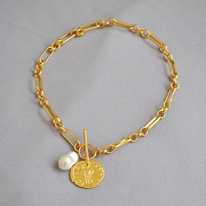 Detalle del colgante moneda de oro con perla barroca y cierre de palanca en cadena