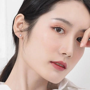 Macro side view of a model wearing minimalist 925 sterling silver square zircon stud earrings