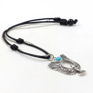 Detail of silver eagle pendant with turquoise stone on multi-layer beaded cord necklace