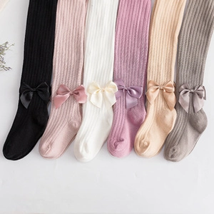 Detail showing colorful cotton knit baby leggings with satin bows on the ankles