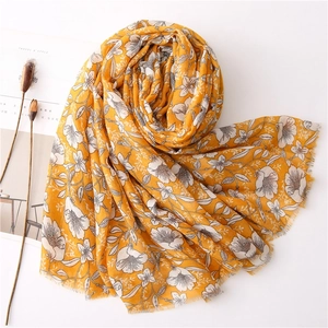 Ginger yellow linen scarf with white gardenia print and fringe, shown in elegant flat lay