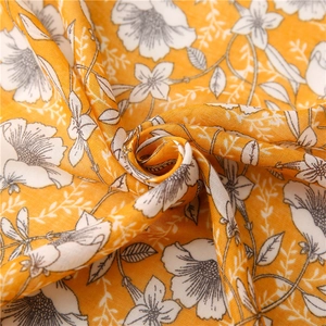 Detailed view of yellow floral print fabric with white flowers and soft draping texture