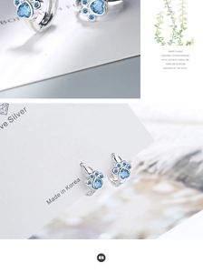 Detailed view of silver cat paw earrings with blue zircon on a Silver brand display card