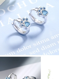 Close-up of silver cat paw earrings with blue heart zircon and sparkling blue stones