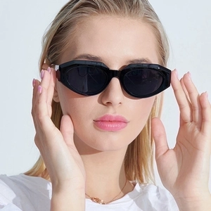 Irregular geometric black cat eye sunglasses with dark UV lenses on a female model
