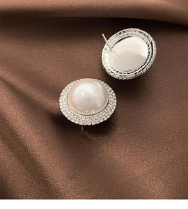 Detailed macro view of luxury round pearl stud earrings with double-row zircon setting