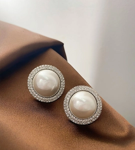 Detailed view of silver stud earrings with large white pearls and sparkling diamond halo