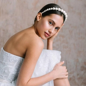 Detail of white pearl beaded headband with ribbon ties on a wedding bride