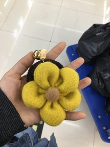 Detail of yellow wool felt flower hair tie with engraved gold metal buckle and elastic band