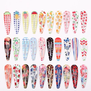 Flat lay of 30 colorful 5cm snap hair clips with fruit and floral patterns on white background