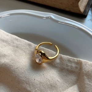 Minimalist 925 silver golden ring with oval zircon on a ceramic plate background