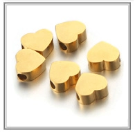 Detailed view of six golden heart-shaped beads with side holes for DIY jewelry making