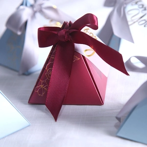 Macro shot of burgundy pyramid gift box with gold floral lines and 'for You' tag