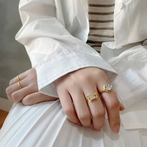 Close-up of a three-piece gold ring set featuring large clear zircon stones on a model