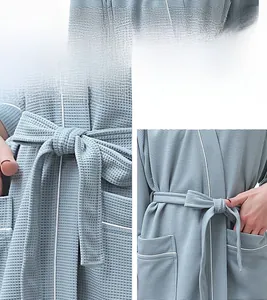 Detail of light blue waffle weave bathrobe with white piping and textured fabric