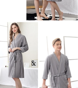 Detail showing high-quality waffle weave texture and white piping on gray bathrobes