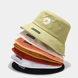 Dettaglio di cappelli a secchiello in tela colorata con ricamo a margherita ed etichetta
