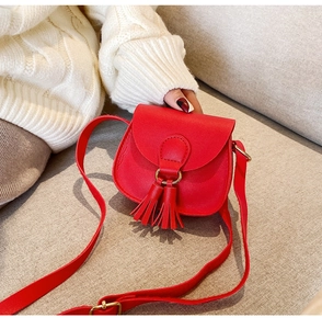 Detailed view of red mini crossbody bag with tassels shown in a lifestyle setting