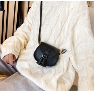 Toddler girl wearing black leather mini crossbody bag with tassel and gold ring detail