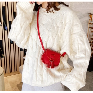 Detail of red mini tassel saddle bag paired with a white knitted sweater for kids