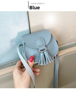 Close-up of light blue mini saddle bag with dual tassel details and golden ring hardware