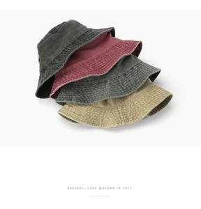 Detail of stacked washed cotton bucket hats in four colors with vintage metal eyelets