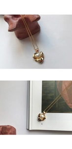 Detail of elegant gold flower petal pendant with a round white pearl on a delicate chain
