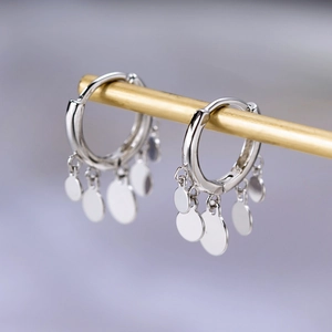 Macro shot of silver tassel hoop earrings with metallic sequins on a gold stand