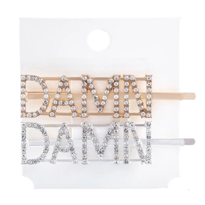 Detailed macro of DAMN letter hair clips with rhinestones in gold and silver finish