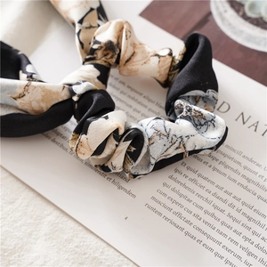 Detail of floral silk scrunchie with cream and blue flowers on a black background