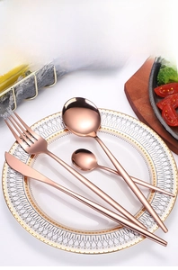 Rose gold stainless steel cutlery set displayed on a white ceramic plate for dining