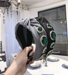 Detail of baroque knotted headband featuring emerald gemstones and sparkling rhinestones