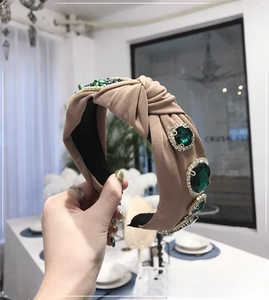 Close-up of emerald green faceted gemstones and rhinestones on a khaki knotted headband