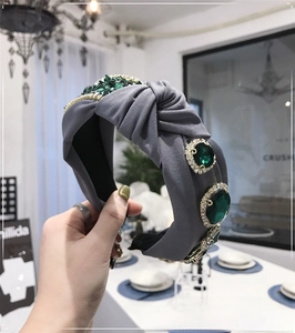 Macro shot of emerald gemstones and crystal beads on a grey knotted velvet headband