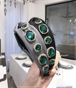 Detail of baroque knotted headbands featuring emerald green crystals and rhinestones